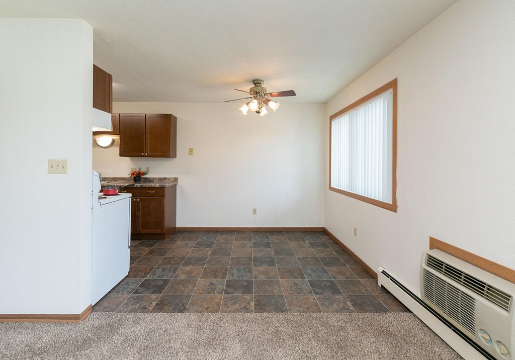 the living room and kitchen of an apartment with a ceiling fan. Fargo, ND Islander Apartments