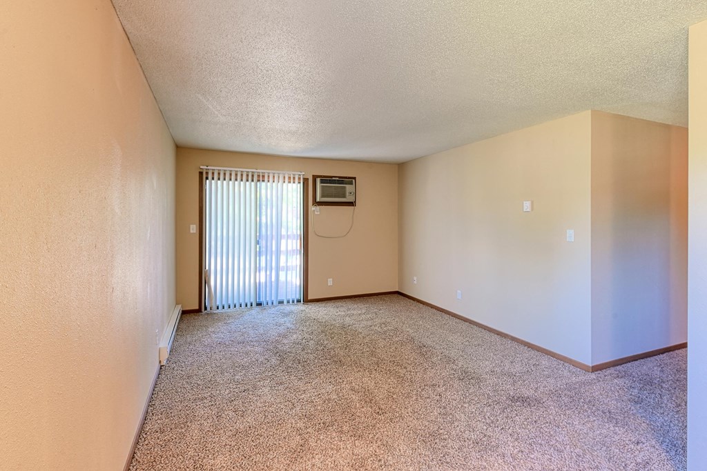 Grand Forks, ND Madison Apartments. A living room with a glass sliding door.