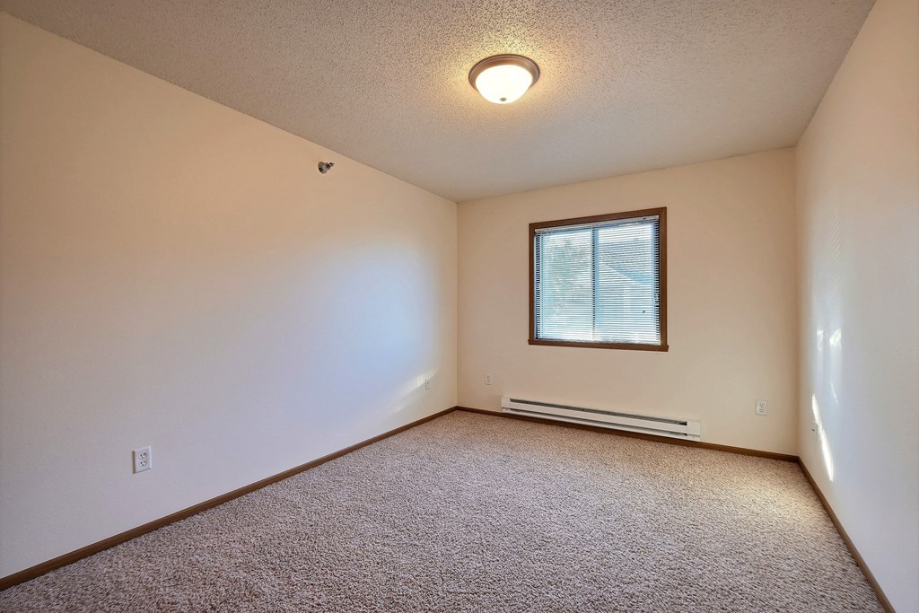 A bedroom with white walls and a window. Fargo, ND Eagle Run Apartments.
