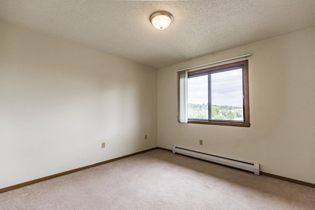 Bismarck, ND Eagle Sky I Apartments. A bedroom with a large window and beige carpet
