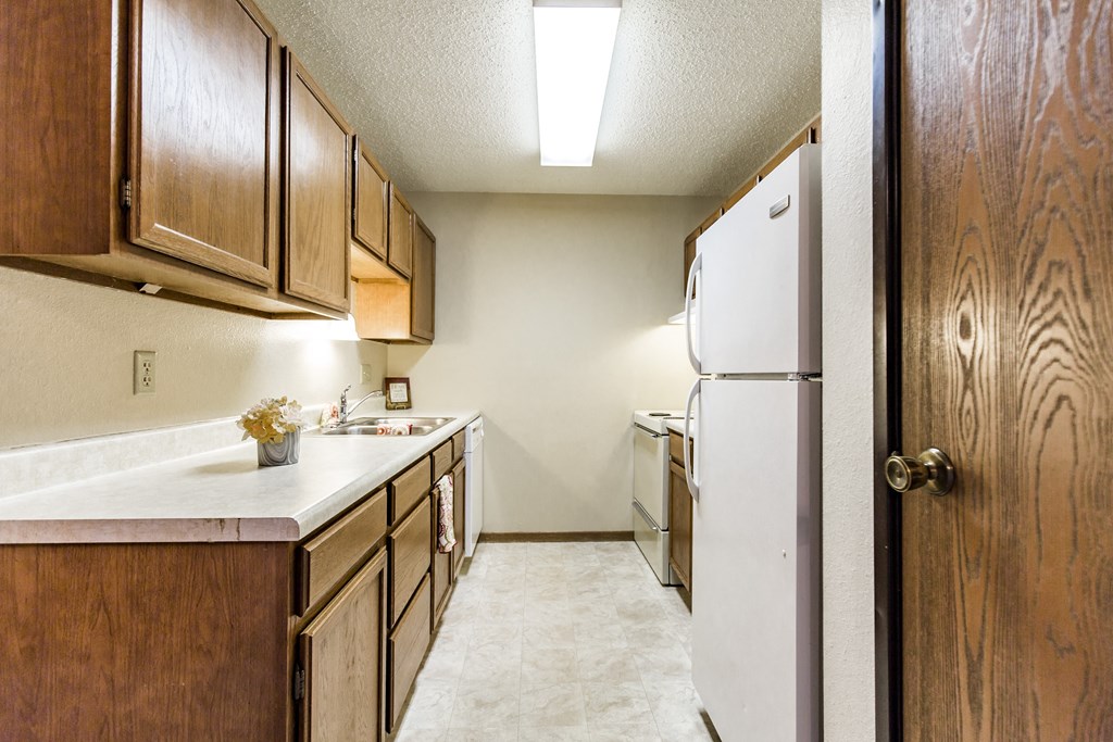 Bismarck, ND Eagle Sky I Apartments. A kitchen with a white refrigerator freezer next to a white stove top oven