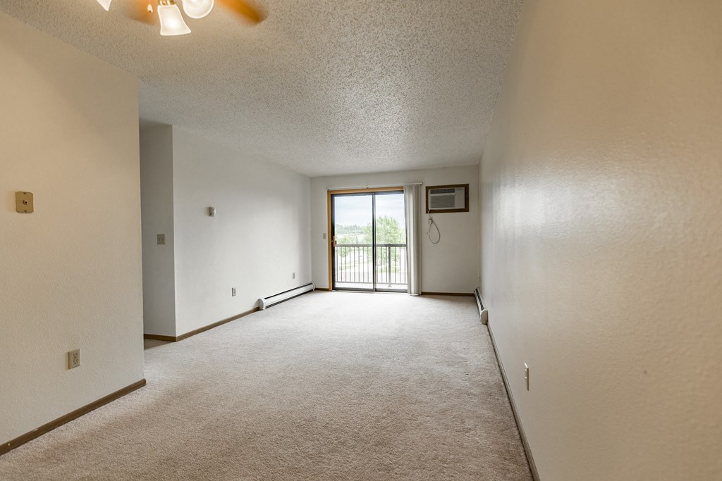 Bismarck, ND Eagle Sky I Apartments. A living room and dining room with a glass sliding door.