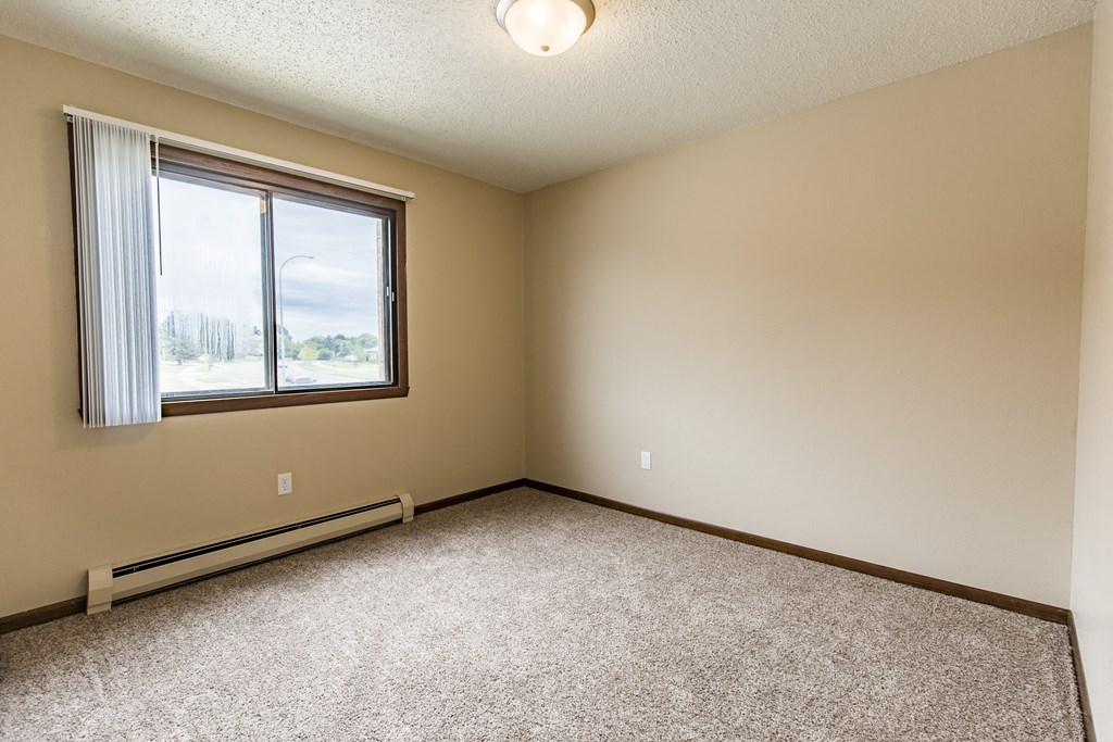 Bismarck, ND Eagle Sky I Apartments. A bedroom with a large window and beige carpet