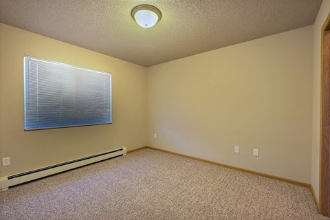 a bedroom with a window and carpet. Fargo, ND East Bridge Apartments