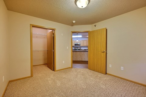 a bedroom with a door open to a closet. Fargo, ND East Bridge Apartments