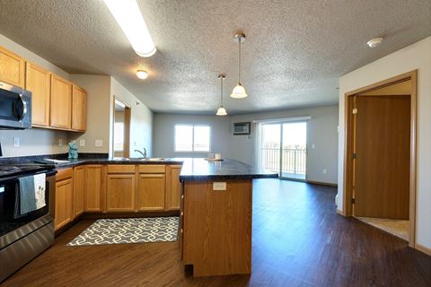 an empty kitchen and living room with wood flooring and a counter top. Fargo, ND East Bridge Apartments