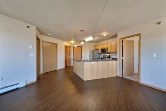a living room and kitchen with wood floors. Fargo, ND East Bridge Apartments