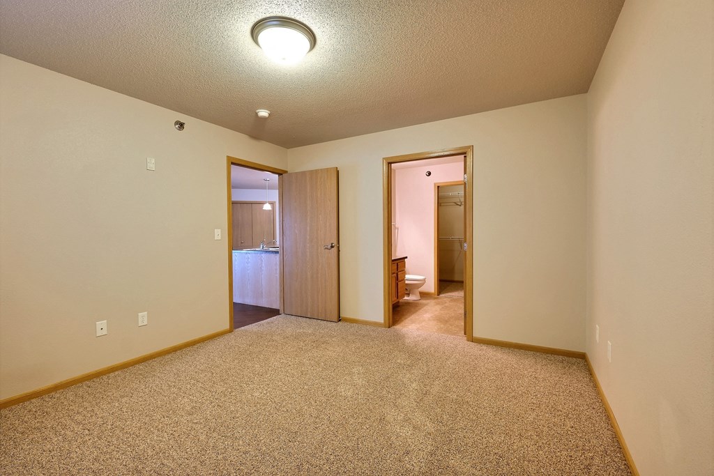 a bedroom with a door to a bathroom. Fargo, ND East Bridge Apartments