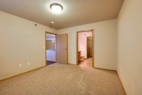 a bedroom with a door to a bathroom. Fargo, ND East Bridge Apartments
