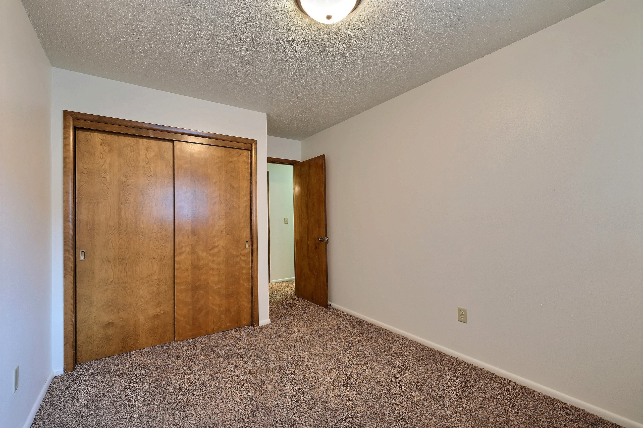 a bedroom with a closet and carpeted floors. Fargo, ND Emerald Apartments