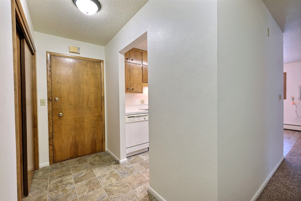 the view of the kitchen from the living room with a wooden door. Fargo, ND Emerald Apartments