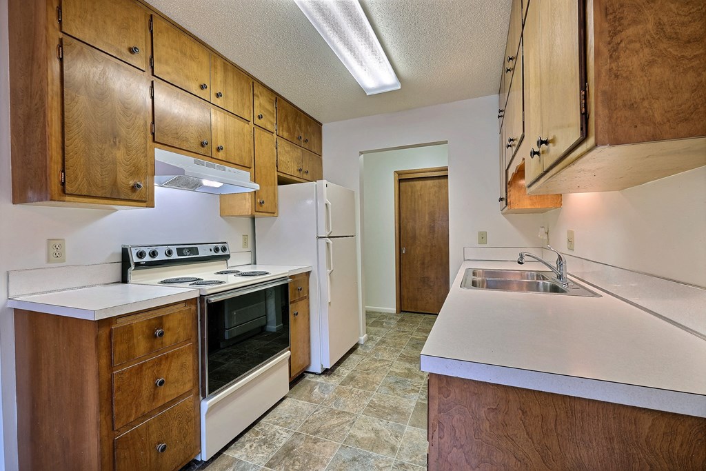 a kitchen with white appliances and wooden cabinets. Fargo, ND Emerald Apartments