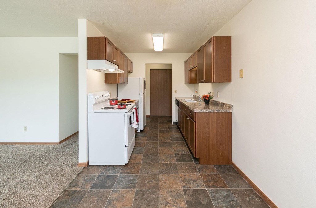 a kitchen with white appliances and wooden cabinets. Fargo, ND Islander Apartments