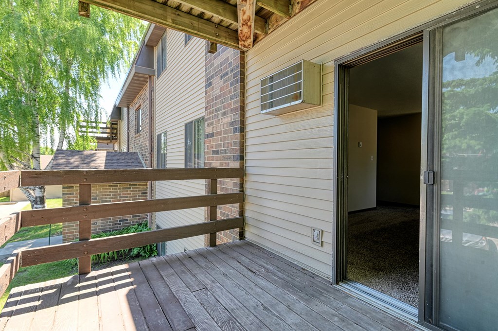 Grand Forks, ND Madison Apartments. A  balcony with a open door into an apartment.