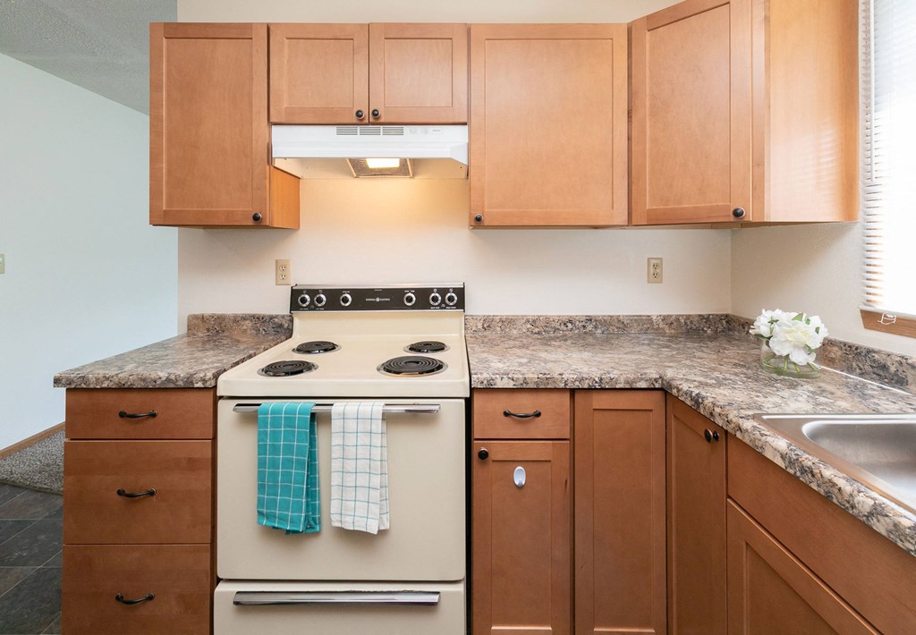 a kitchen with wooden cabinets and a stove. Fargo, ND White Ridge Apartments.