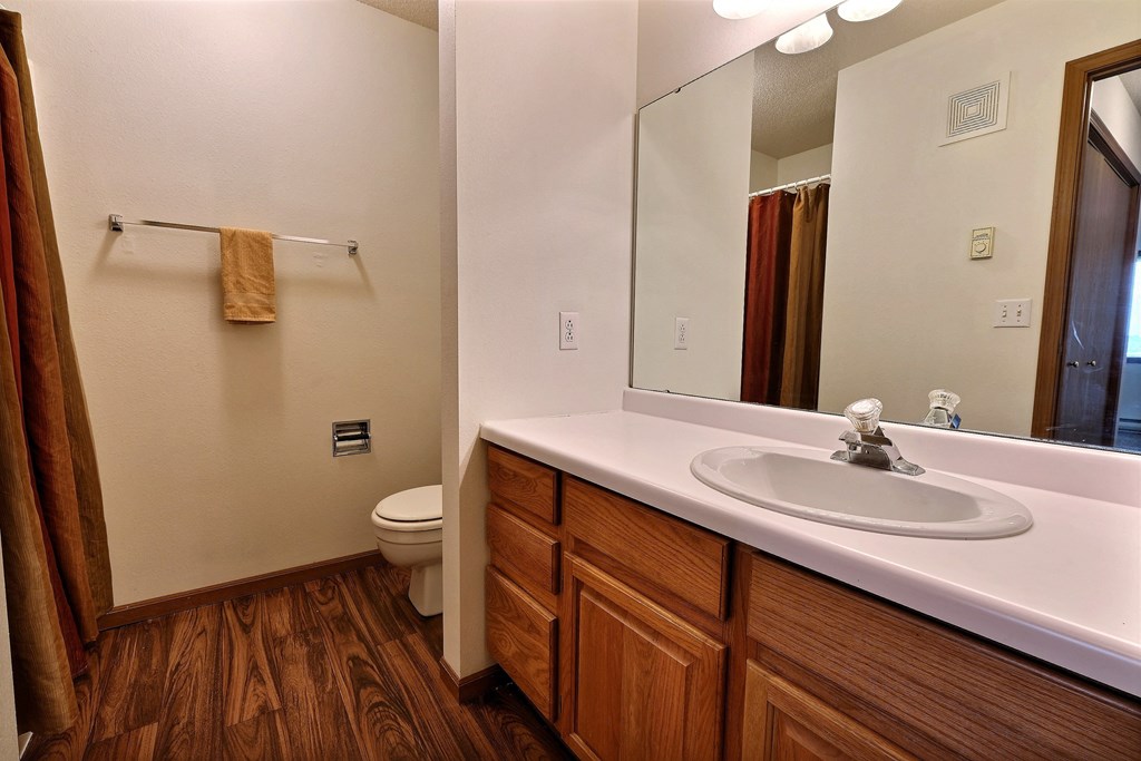 A bathroom with a sink and a toilet and a mirror. Fargo, ND Flagstone Apartments.