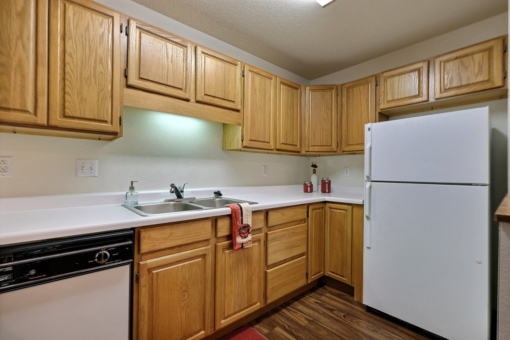 A kitchen with white appliances and wooden cabinets. Fargo, ND Flagstone Apartments.