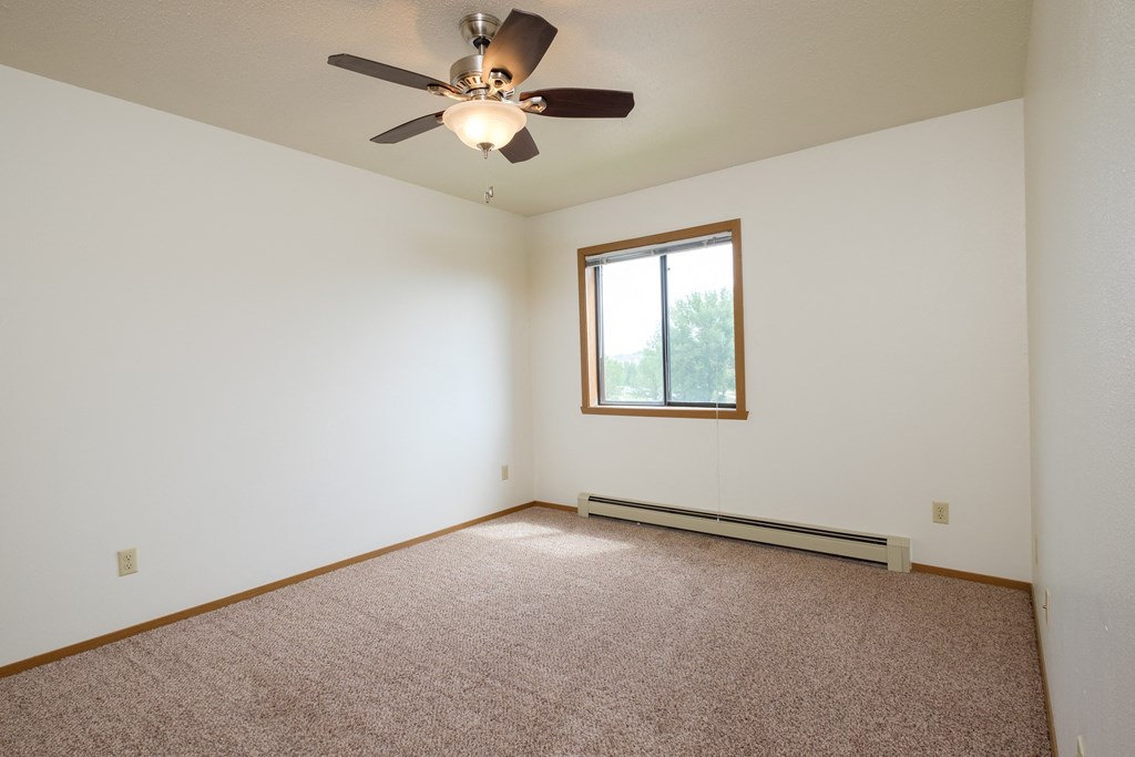 a bedroom with a ceiling fan and a window. Fargo, ND Flickertail Apartments