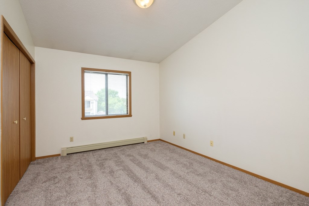 a bedroom with carpet and a window. Fargo, ND Flickertail Apartments