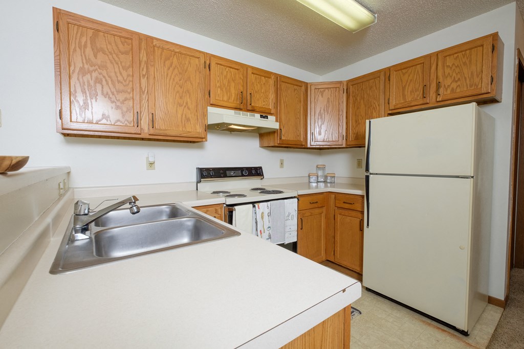 a kitchen with white appliances and wooden cabinets. Fargo, ND Flickertail Apartments