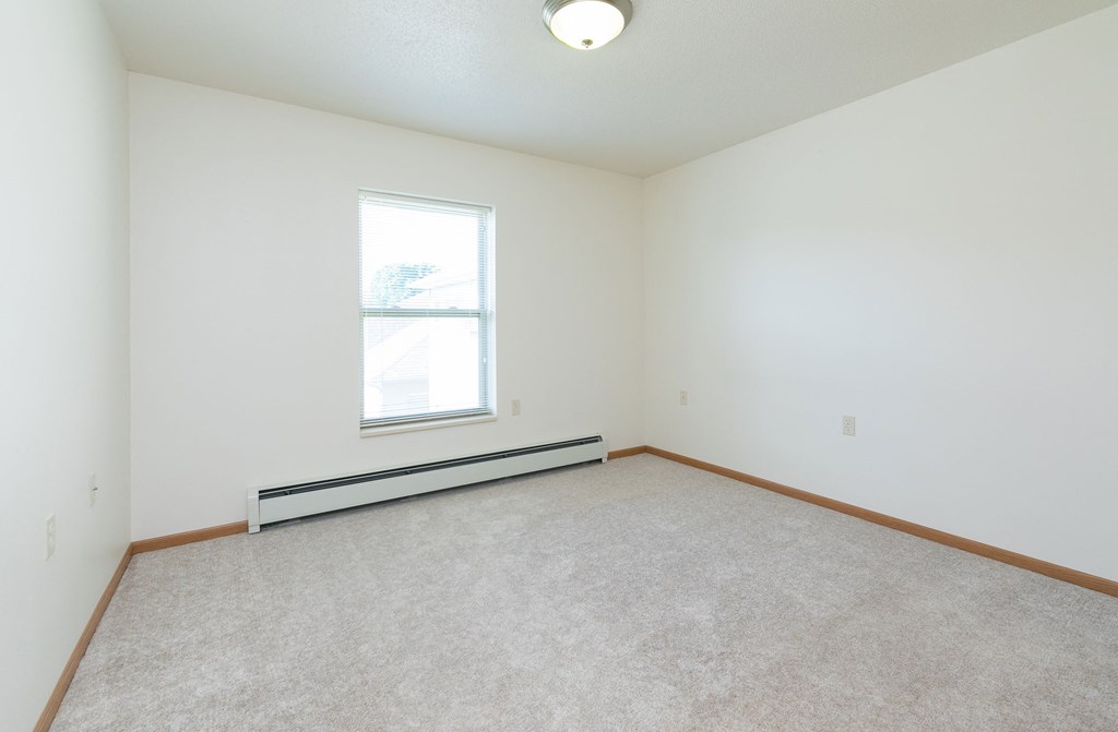 a bedroom with a window and a carpeted floor. Fargo, ND Sunrise North