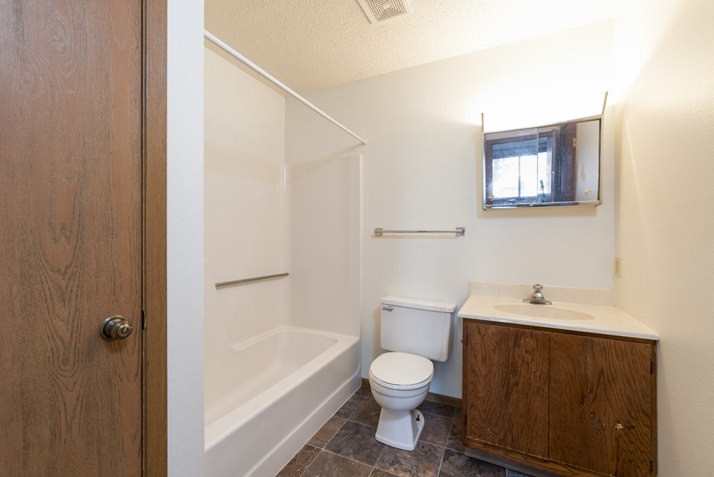 Mandan, ND Garden Grove Apartments. A bathroom with a toilet sink and bathtub