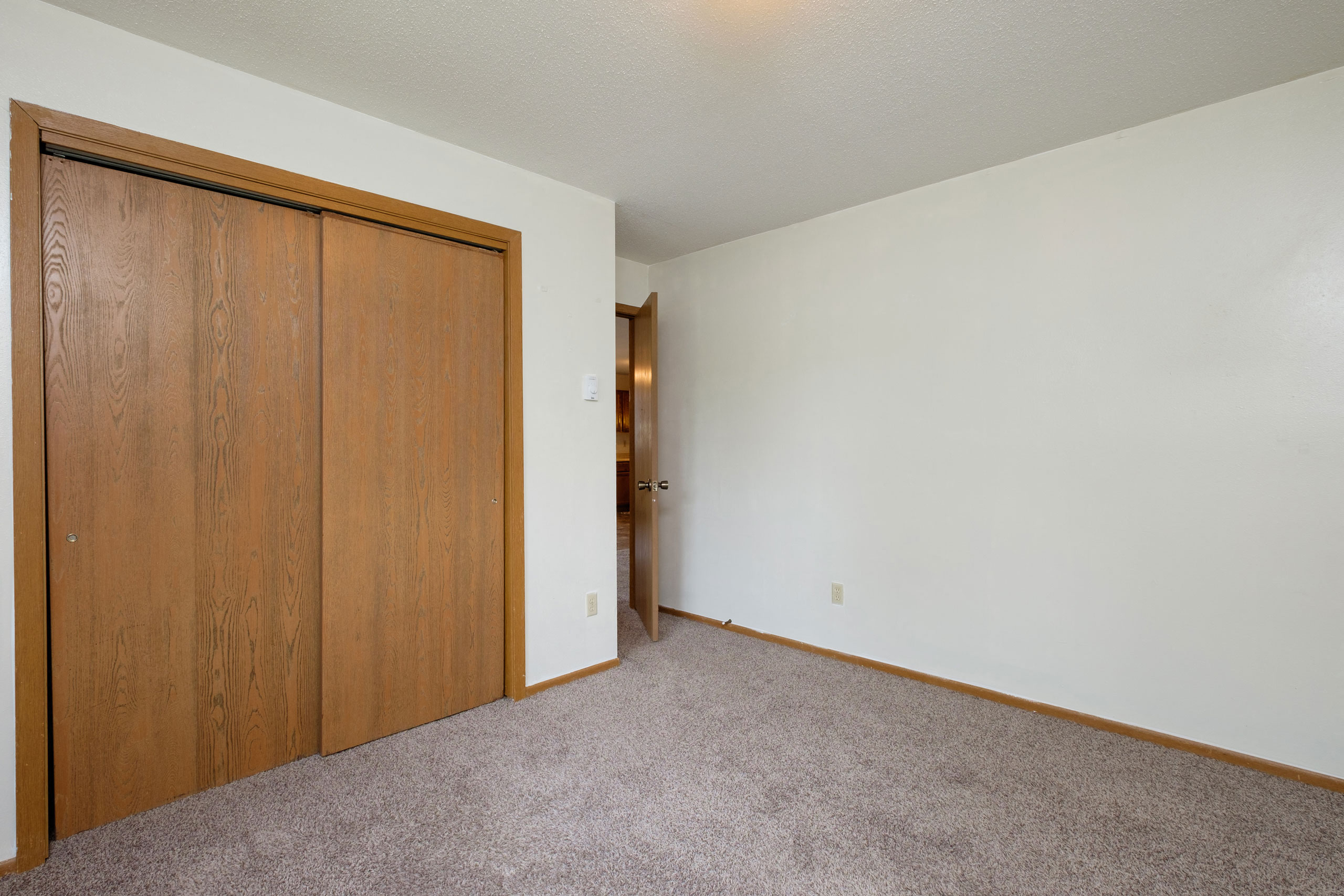 a bedroom with a closet and a door to a hallway. Fargo, ND Gemstone Apartments