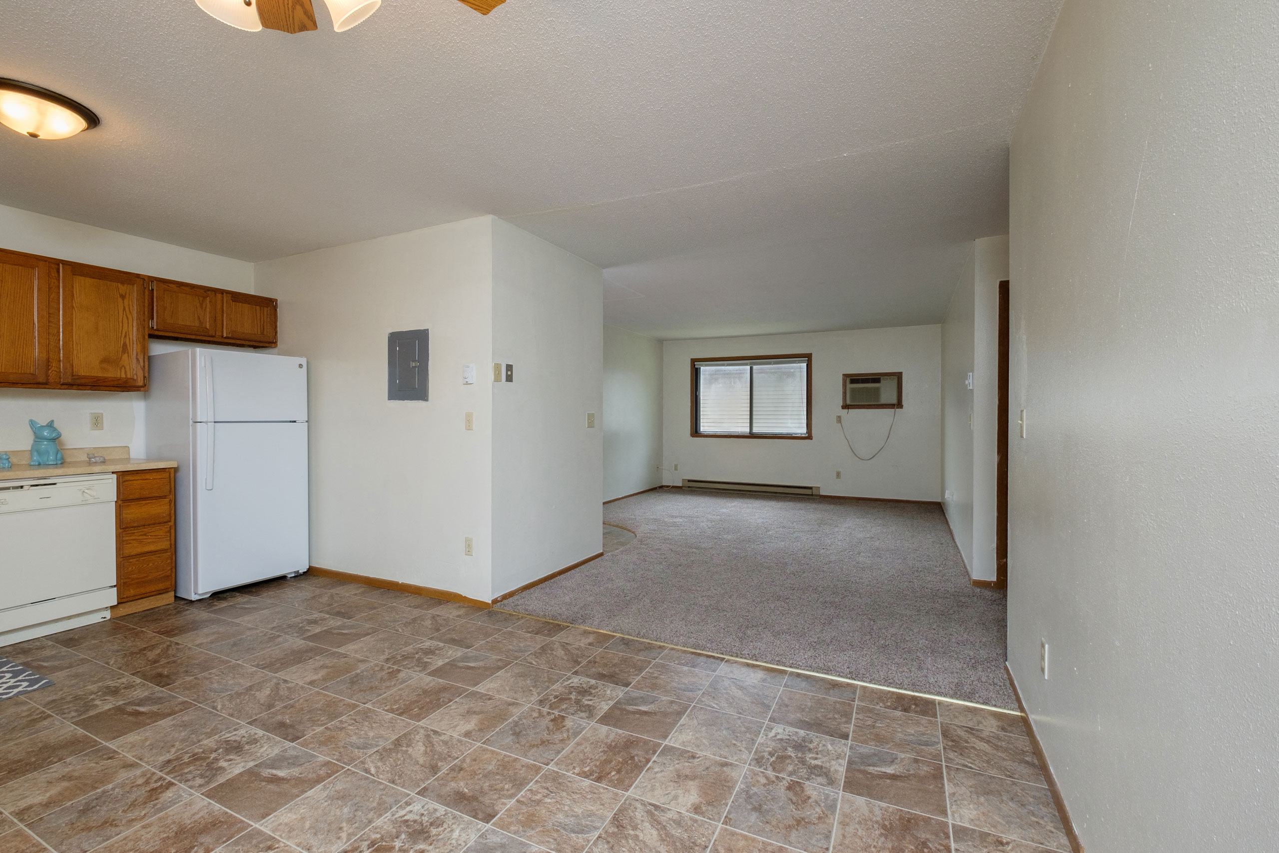 a kitchen with a living room with windows in the background. Fargo, ND Gemstone Apartments