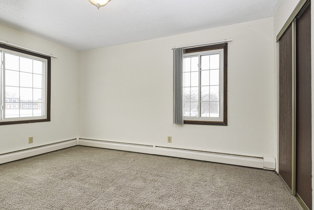 a bedroom with two windows and a carpet. Fridley, MN Georgetown on the River Apartments
