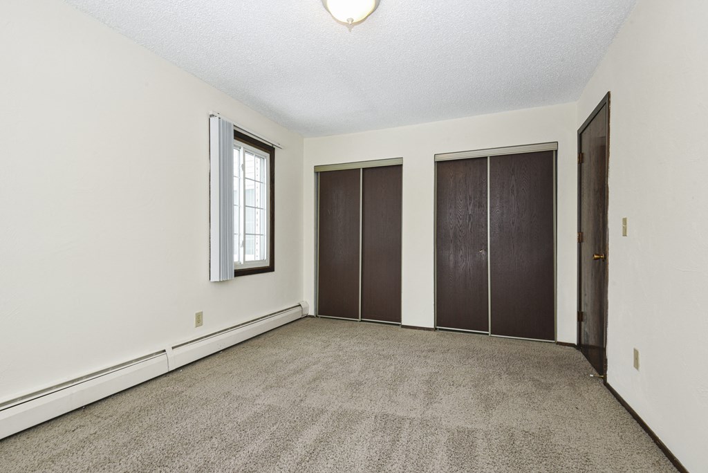 a bedroom with two closets and a window. Fridley, MN Georgetown on the River Apartments