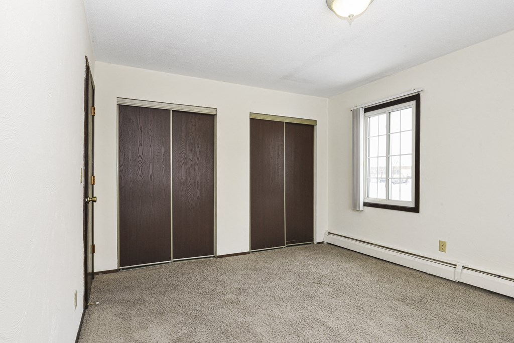 an empty room with a window and two closet doors. Fridley, MN Georgetown on the River Apartments