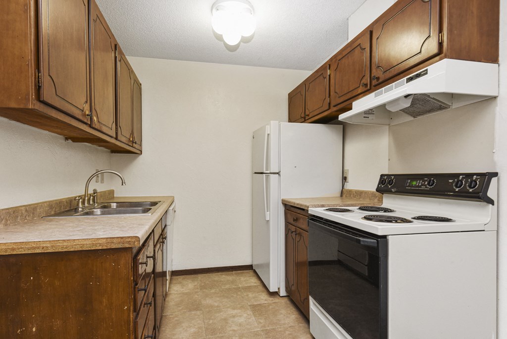 a kitchen with a stove refrigerator and sink. Fridley, MN Georgetown on the River Apartments