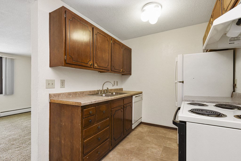 an empty kitchen with a stove refrigerator and sink. Fridley, MN Georgetown on the River Apartments
