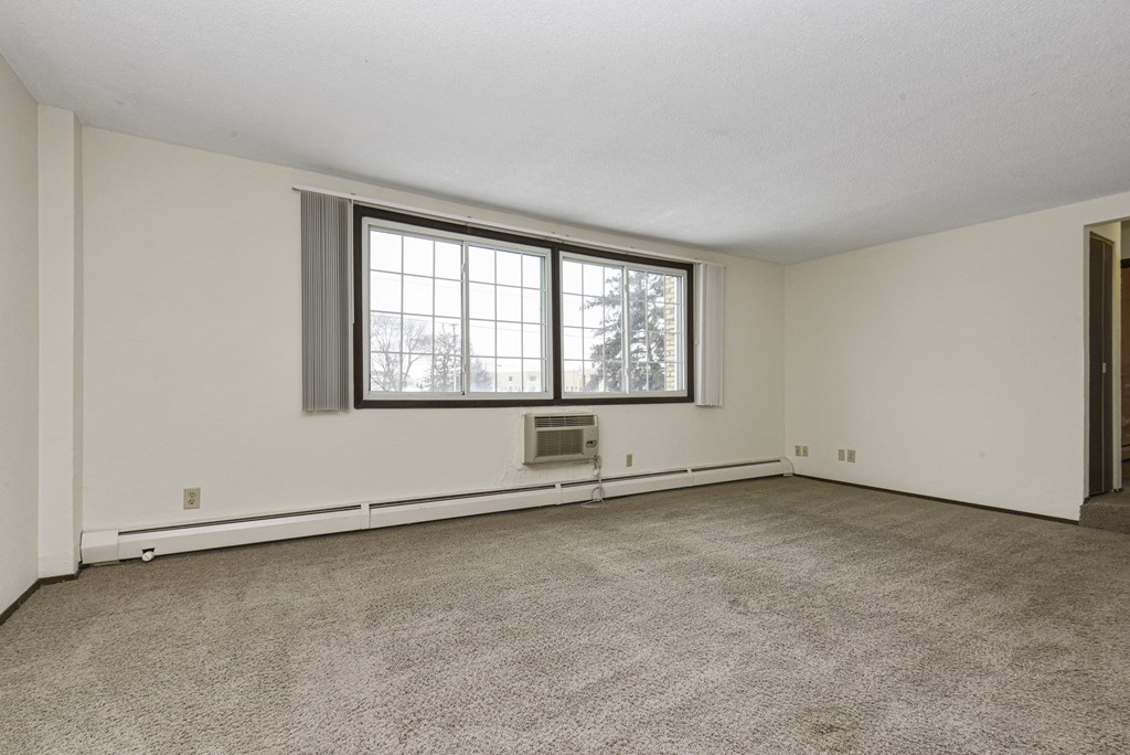 the living room of an empty house with a large window. Fridley, MN Georgetown on the River Apartments