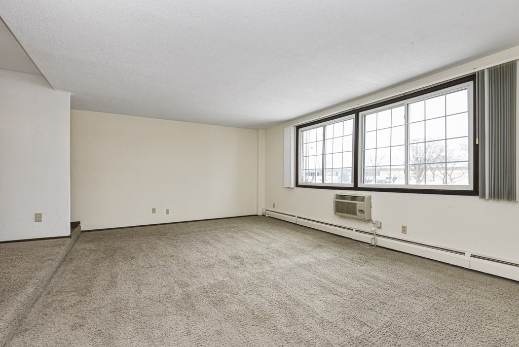 the living room of an empty house with a large window. Fridley, MN Georgetown on the River Apartments
