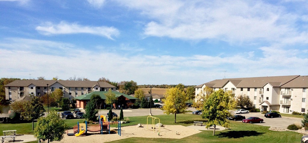 a park with a playground and apartment buildings in the background
