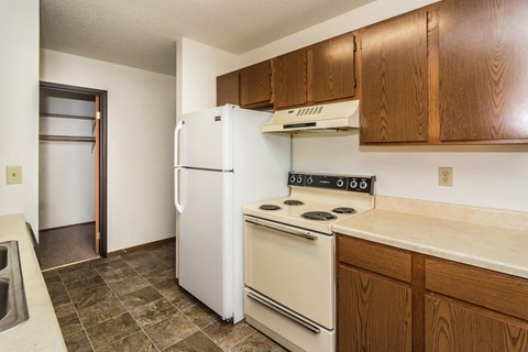 Grand Forks, ND Grandview I Apartments. a kitchen with white appliances and wooden cabinets