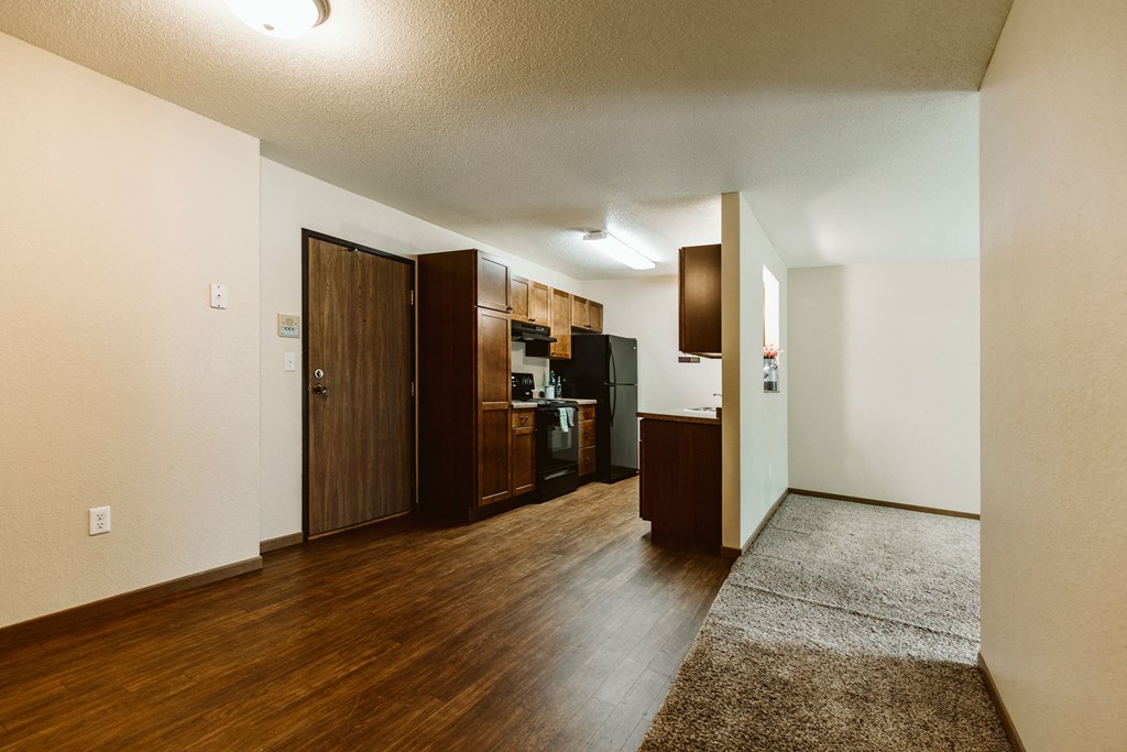 Grand Forks, ND Grandview II Apartments. A kitchen with black appliances and wood floors with a dining room and living slightly in shot.