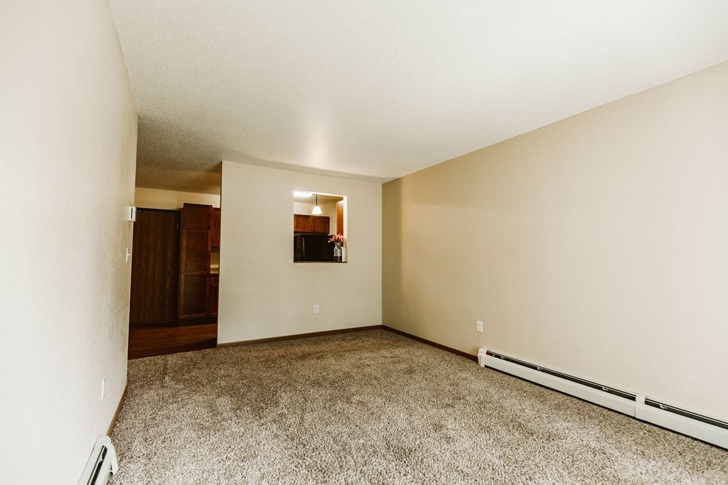 Grand Forks, ND Grandview II Apartments | Living Grand Forks, ND Grandview II Apartments. A living room with baseboard heaters and a dining room in the background