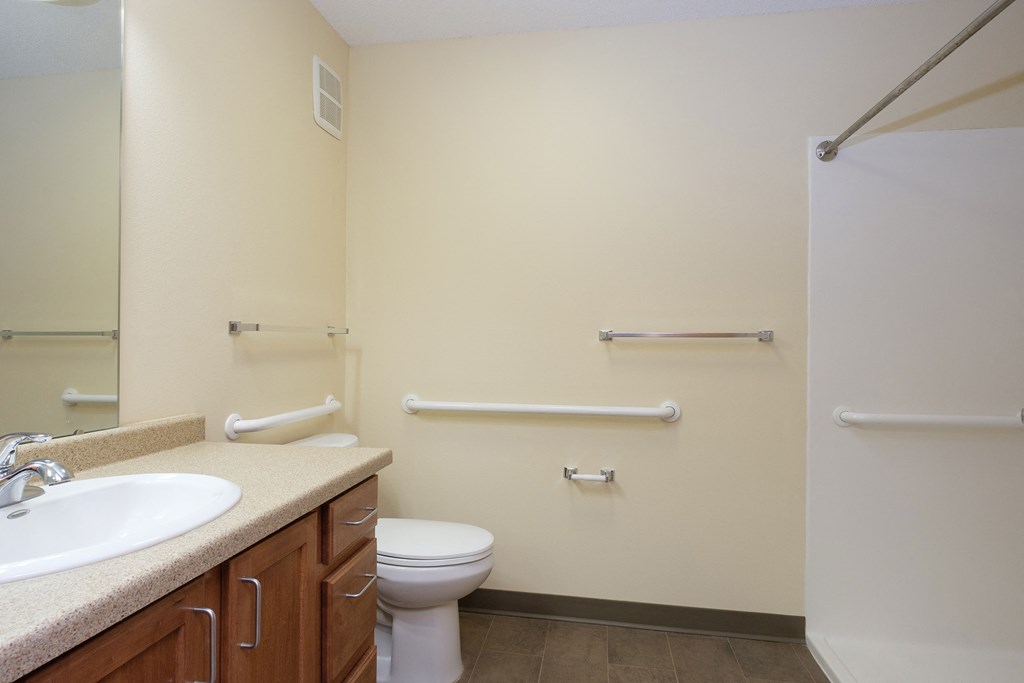 a bathroom with a sink and a toilet and a shower. Fargo, ND Crossroads Apartments