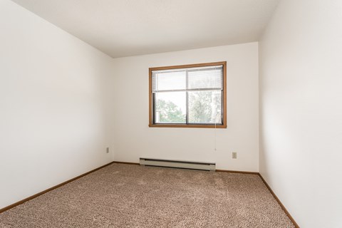 Grand Forks Harrison Apartments. A bedroom with carpet and a window
