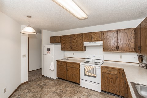 Grand Forks Harrison Apartments. A kitchen with white appliances and wooden cabinets
