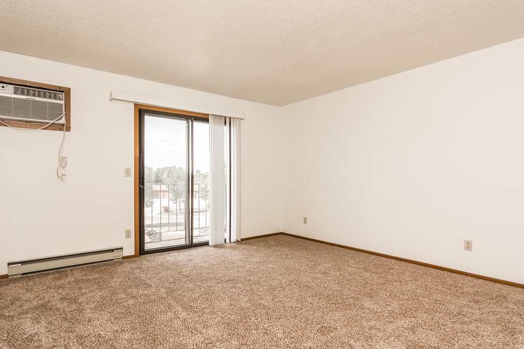 Grand Forks Harrison Apartments. An empty living room with a sliding glass door to a balcony