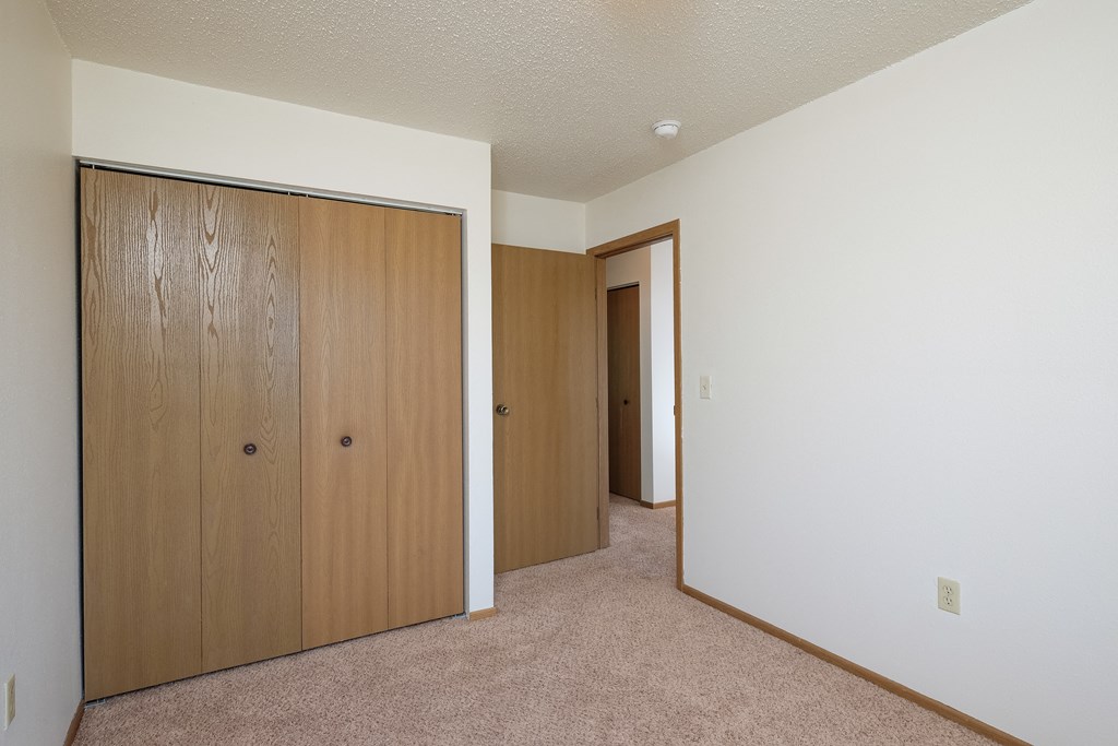 a bedroom with two closets and a door to a hallway. Fargo, ND Hazelwood Townhomes