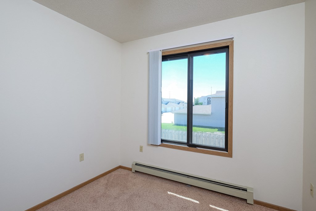 an empty room with a window and a carpet. Fargo, ND Hazelwood Townhomes