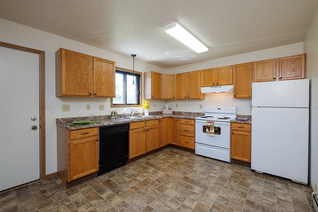 a kitchen with white appliances and wooden cabinets. Fargo, ND Hazelwood Townhomes