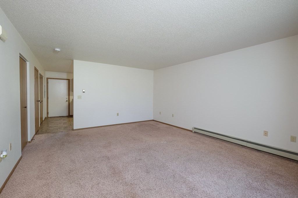 an empty living room with carpet and white walls. Fargo, ND Hazelwood Townhomes