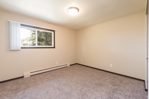 Bismarck, ND Highland Meadows Apartments. An empty bedroom with a large window and carpet