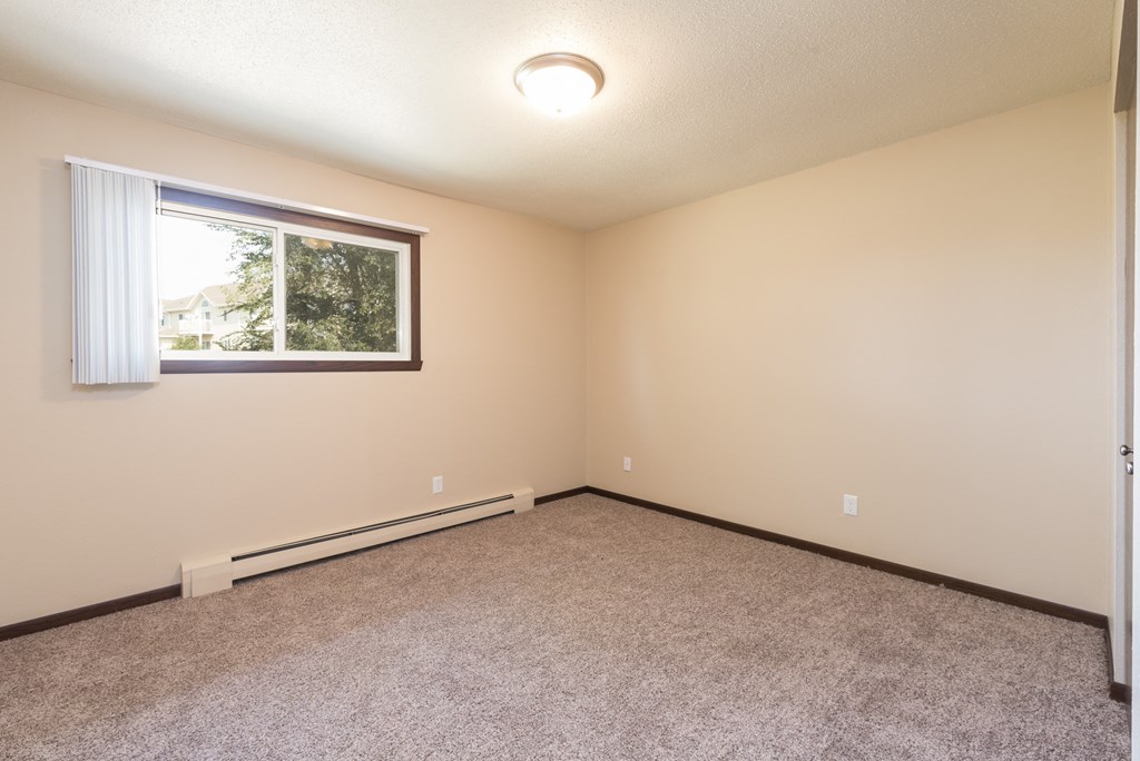 Bismarck, ND Highland Meadows Apartments | Bedroom Bismarck, ND Highland Meadows Apartments. An empty bedroom with a large window and carpet