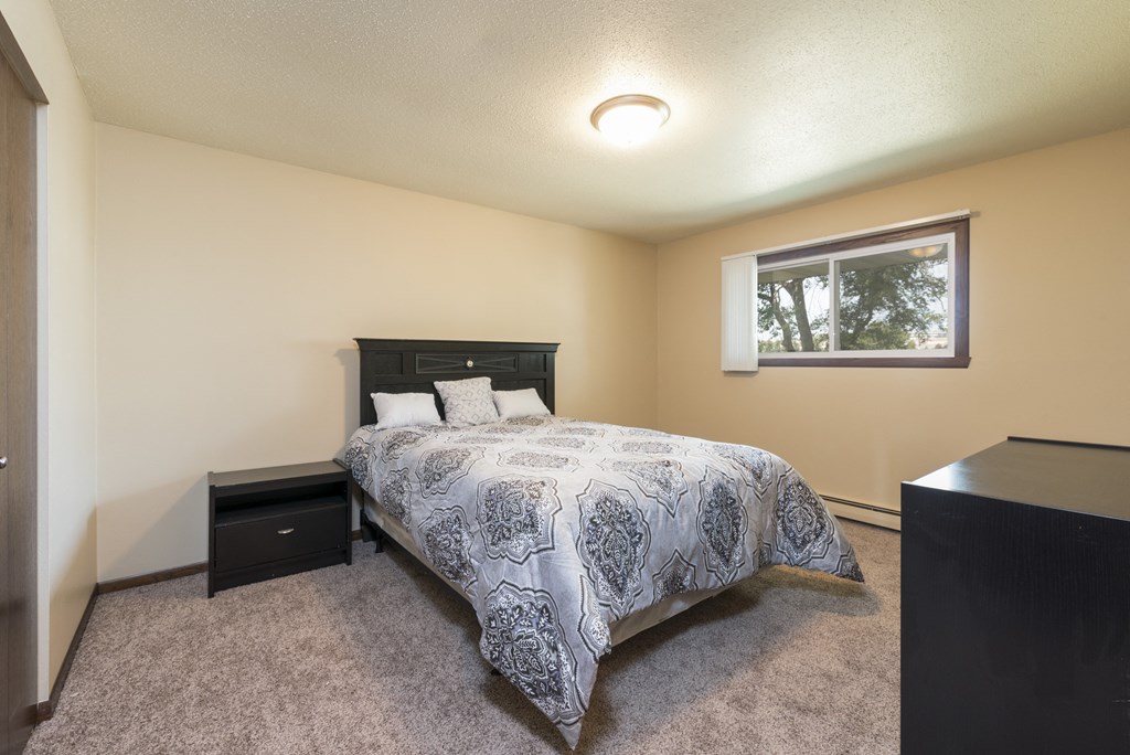 Bismarck, ND Highland Meadows Apartments | Bedroom a bedroom with a bed and a window. Bismarck, ND Highland Meadows Apartments